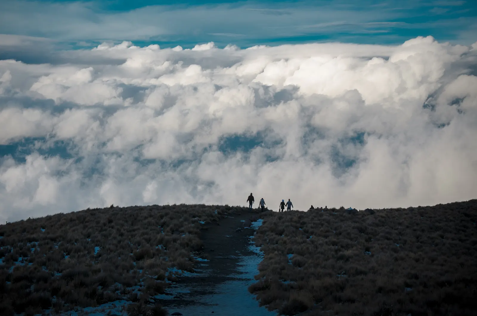 Trekkers on a mountain path above the clouds
