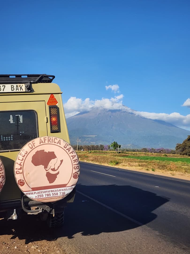 Places of Africa Safaris 4x4 Land Cruiser on the road with Mount Meru behind