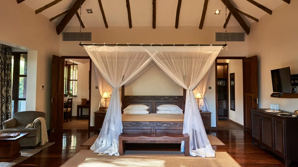 Legendary Lodge: Bedroom with wooden four-poster bed and white sheer curtains, hardwood floors