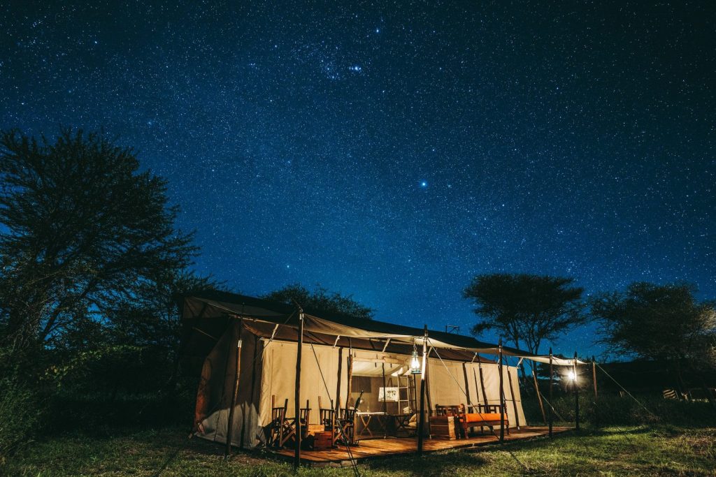 Lemala Ewanjan Tented Camp: Guest tent with furnished wooden deck lit up at night under a starry sky