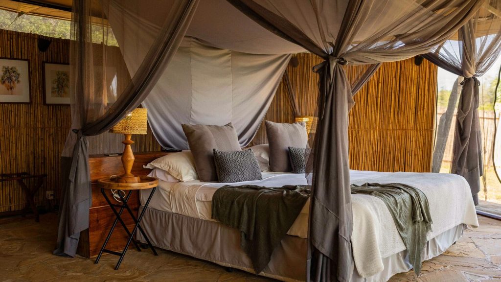 Roho ya Selous: Guest tent interior with canopy bed, wooden furnishings and neutral decor
