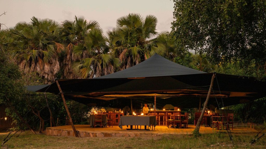 Roho ya Selous: Open-air dining area under a canopy, candle-lit at dusk